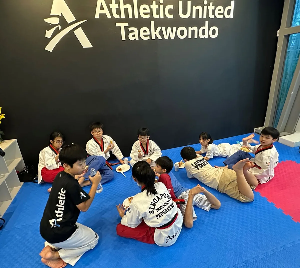 Kids taekwondo students sharing a meal together on the mats after training